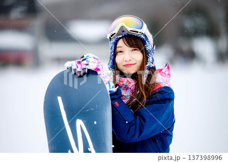 スキー場のゲレンデでウィンタースポーツのスノーボードを楽しむ若い女性 137398996