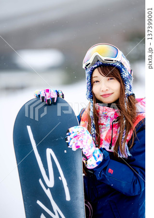スキー場のゲレンデでウィンタースポーツのスノーボードを楽しむ若い女性 137399001