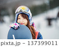 スキー場のゲレンデでウィンタースポーツのスノーボードを楽しむ若い女性 137399011