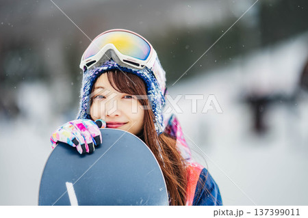 スキー場のゲレンデでウィンタースポーツのスノーボードを楽しむ若い女性 137399011