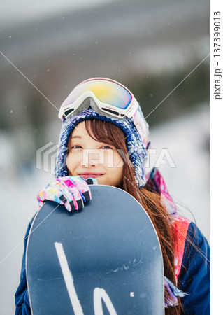 スキー場のゲレンデでウィンタースポーツのスノーボードを楽しむ若い女性 スキー場のゲレンデでウィンタースポーツのスノーボードを楽しむ若い女性 137399013