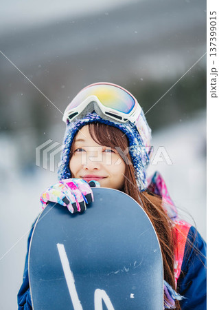 スキー場のゲレンデでウィンタースポーツのスノーボードを楽しむ若い女性 スキー場のゲレンデでウィンタースポーツのスノーボードを楽しむ若い女性 137399015