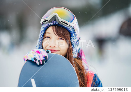 スキー場のゲレンデでウィンタースポーツのスノーボードを楽しむ若い女性 スキー場のゲレンデでウィンタースポーツのスノーボードを楽しむ若い女性 137399018