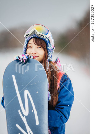スキー場のゲレンデでウィンタースポーツのスノーボードを楽しむ若い女性 スキー場のゲレンデでウィンタースポーツのスノーボードを楽しむ若い女性 137399027