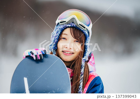 スキー場のゲレンデでウィンタースポーツのスノーボードを楽しむ若い女性 137399043