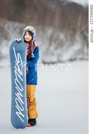 スキー場のゲレンデでウィンタースポーツのスノーボードを楽しむ若い女性 137399060