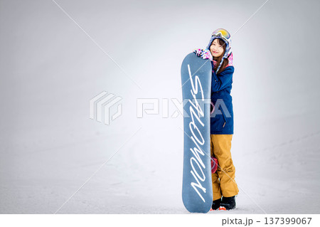 スキー場のゲレンデでウィンタースポーツのスノーボードを楽しむ若い女性 137399067