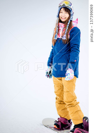 スキー場のゲレンデでウィンタースポーツのスノーボードを楽しむ若い女性 137399069
