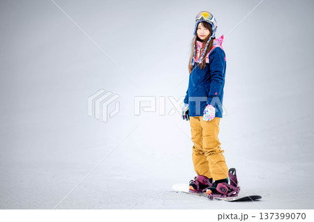 スキー場のゲレンデでウィンタースポーツのスノーボードを楽しむ若い女性 137399070