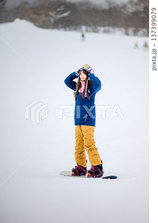 スキー場のゲレンデでウィンタースポーツのスノーボードを楽しむ若い女性 137399079
