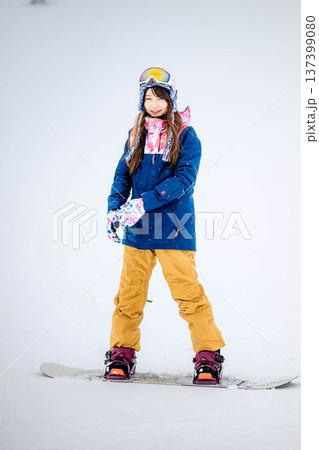 スキー場のゲレンデでウィンタースポーツのスノーボードを楽しむ若い女性 137399080