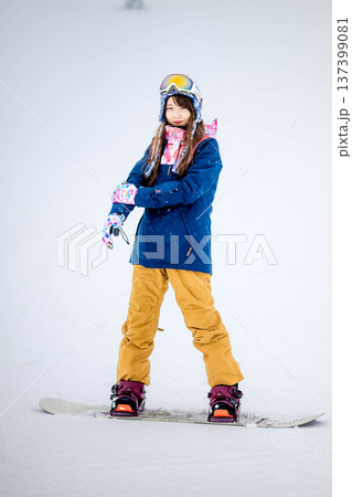 スキー場のゲレンデでウィンタースポーツのスノーボードを楽しむ若い女性 137399081