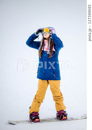 スキー場のゲレンデでウィンタースポーツのスノーボードを楽しむ若い女性 137399085