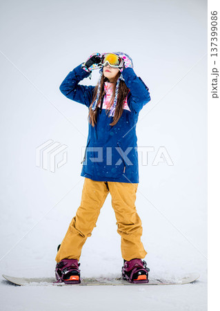 スキー場のゲレンデでウィンタースポーツのスノーボードを楽しむ若い女性 137399086