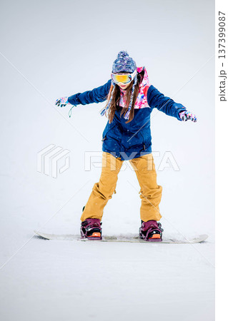 スキー場のゲレンデでウィンタースポーツのスノーボードを楽しむ若い女性 137399087