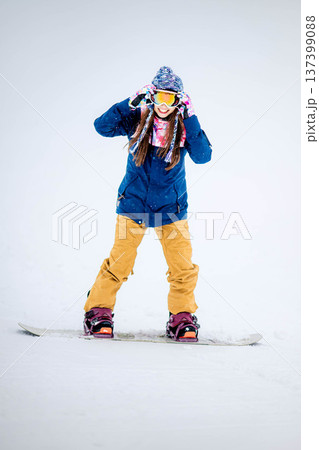 スキー場のゲレンデでウィンタースポーツのスノーボードを楽しむ若い女性 スキー場のゲレンデでウィンタースポーツのスノーボードを楽しむ若い女性 137399088