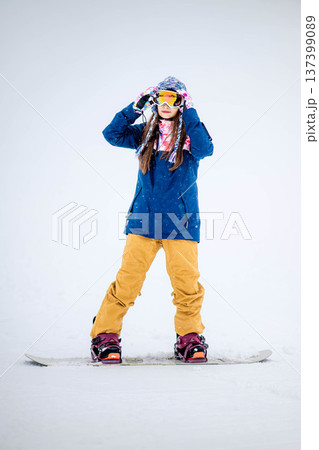 スキー場のゲレンデでウィンタースポーツのスノーボードを楽しむ若い女性 137399089