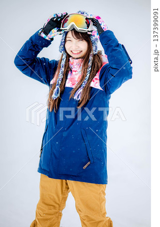 スキー場のゲレンデでウィンタースポーツのスノーボードを楽しむ若い女性 137399091