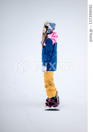 スキー場のゲレンデでウィンタースポーツのスノーボードを楽しむ若い女性 137399092