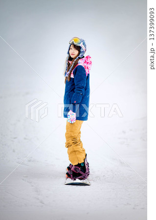 スキー場のゲレンデでウィンタースポーツのスノーボードを楽しむ若い女性 スキー場のゲレンデでウィンタースポーツのスノーボードを楽しむ若い女性 137399093