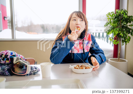 スキーウェアを着て休憩しながら食事をとる若い女性 スキーウェアを着て休憩しながら食事をとる若い女性 137399271