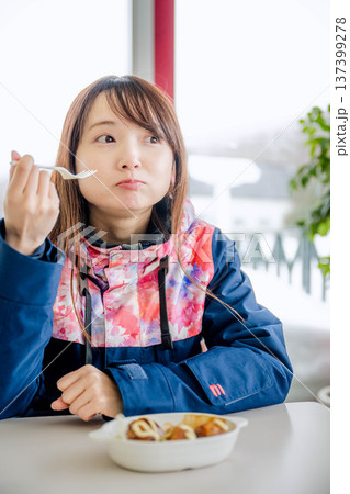 スキーウェアを着て休憩しながら食事をとる若い女性 スキーウェアを着て休憩しながら食事をとる若い女性 137399278