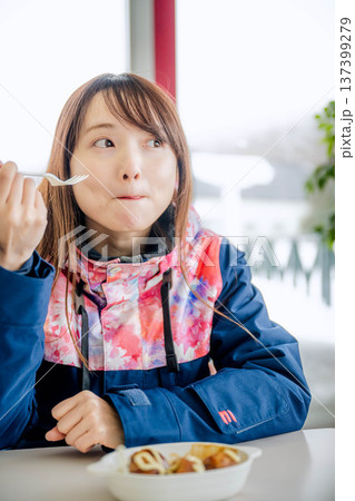 スキーウェアを着て休憩しながら食事をとる若い女性 137399279