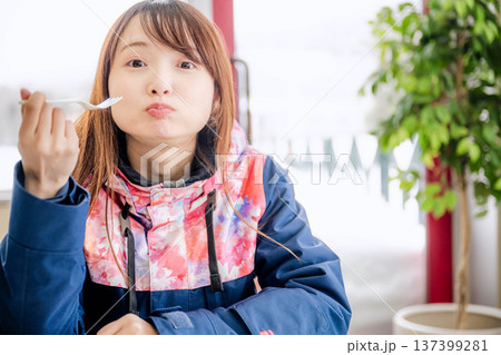 スキーウェアを着て休憩しながら食事をとる若い女性 スキーウェアを着て休憩しながら食事をとる若い女性 137399281