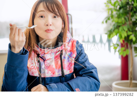 スキーウェアを着て休憩しながら食事をとる若い女性 スキーウェアを着て休憩しながら食事をとる若い女性 137399282