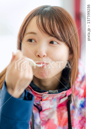 スキーウェアを着て休憩しながら食事をとる若い女性 スキーウェアを着て休憩しながら食事をとる若い女性 137399286