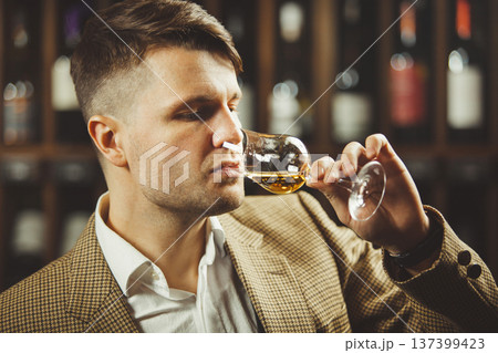 Caucasian sommelier tasting whiskey taste on the cellar background. Caucasian sommelier tasting whiskey taste on the cellar background. 137399423