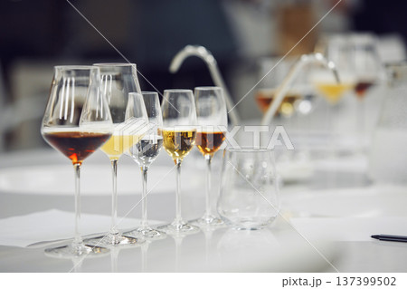 Various alcoholic beverages in glasses in white table in wine room. Sommelier school, professional certification, winemaking association. Various alcoholic beverages in glasses in white table in wine room. Sommelier school, professional certification, winemaking association. 137399502
