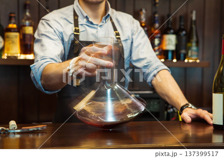 Bartender decanting wine without disturbing the sediment 137399517