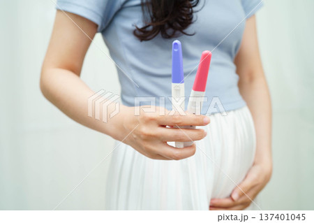 Asian holding pregnancy test for female of ovulation day, fetus, maternity, childbirth, birth control. Asian holding pregnancy test for female of ovulation day, fetus, maternity, childbirth, birth control. 137401045