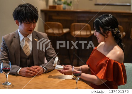 レストランでプロポーズをする男性と指輪を受け取る女性 レストランでプロポーズをする男性と指輪を受け取る女性 137401576