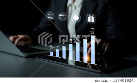 Business Professional Analyzing Digital Graphs and Data on a Laptop and Tablet with E-commerce and Finance Icons in a Dark Office Setting Quark Business Professional Analyzing Digital Graphs and Data on a Laptop and Tablet with E-commerce and Finance Icons in a Dark Office Setting Quark 137401924