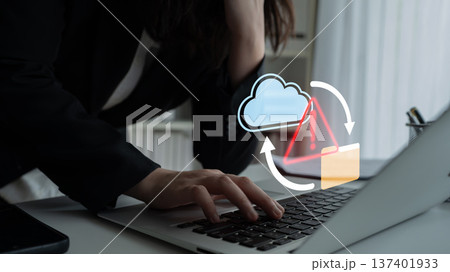 Business professional experiencing frustration with cloud data management while using a laptop in a modern workspace with warning symbols overlay Gantry 137401933