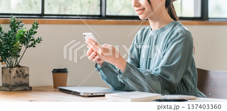 カフェでスマホを使う若いアジア人ビジネスウーマン 137403360