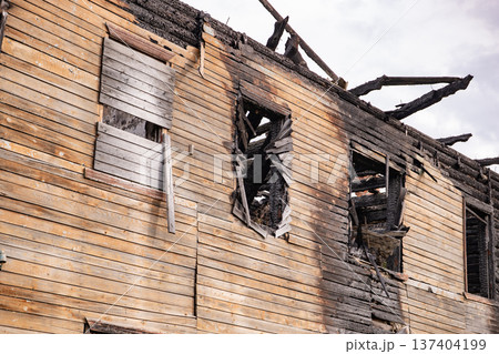 Fire damage destroying residential building, charred wood and gaping windows from disaster Fire damage destroying residential building, charred wood and gaping windows from disaster 137404199