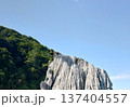 青空の下にそびえる仏ヶ浦の白い奇岩と緑の山並み 137404557
