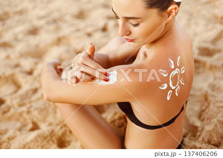 Skin care. Sun protection. Woman apply sun cream. Girl Holding Moisturizing Sunblock. Woman With Suntan Lotion On Beach In Form Of The Sun. Portrait Of Female With Drawn Sun On A Shoulder. Suncream. Skin care. Sun protection. Woman apply sun cream. Girl Holding Moisturizing Sunblock. Woman With Suntan Lotion On Beach In Form Of The Sun. Portrait Of Female With Drawn Sun On A Shoulder. Suncream. 137406206