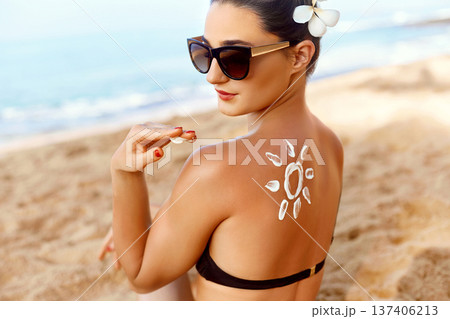 Woman apply Sun cream on tanned back. Skin and Body Care. Sun protection. Portrait of Female in Bikini applying moisturizing sunscreen lotion and Sunblock. Girl Holding Suntan Lotion. Woman apply Sun cream on tanned back. Skin and Body Care. Sun protection. Portrait of Female in Bikini applying moisturizing sunscreen lotion and Sunblock. Girl Holding Suntan Lotion. 137406213