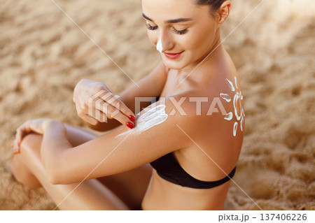 Suntan Lotion. Sexy Young Woman Applying Sunscreen Solar Cream on the beach.Sun Protection. Sun Cream. Skin and Body Care.Girl Holding Moisturizing Sunblock. Sun shape on the shoulder. Skin Protection Suntan Lotion. Sexy Young Woman Applying Sunscreen Solar Cream on the beach.Sun Protection. Sun Cream. Skin and Body Care.Girl Holding Moisturizing Sunblock. Sun shape on the shoulder. Skin Protection 137406226