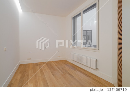 Empty room with wooden floor and large window. White walls and minimalistic design create a spacious feel. Natural light illuminates the area. Empty room with wooden floor and large window. White walls and minimalistic design create a spacious feel. Natural light illuminates the area. 137406719