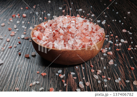 Wooden bowl filled with pink Himalayan salt crystals on dark wooden table, natural mineral seasoning for healthy cooking and spa concepts. Wooden bowl filled with pink Himalayan salt crystals on dark wooden table, natural mineral seasoning for healthy cooking and spa concepts. 137406782