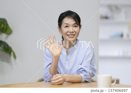 カメラ目線に向かって手を振る50代後半の女性 137406897