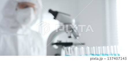 Scientific researcher wearing protective gear, carefully pipetting liquid into test tubes while conducting medical research experiment in laboratory. Medicine, healthcare and science concept Scientific researcher wearing protective gear, carefully pipetting liquid into test tubes while conducting medical research experiment in laboratory. Medicine, healthcare and science concept 137407143