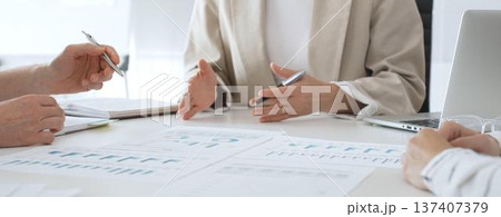 Professional team reviewing financial charts, collaborating on data analysis and strategic planning in modern corporate workspace, emphasizing teamwork and productivity 137407379