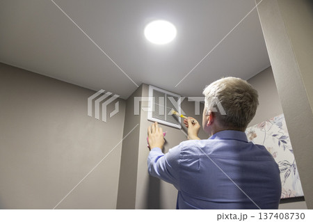 A person installing or maintaining an HVAC return air vent grille 137408730