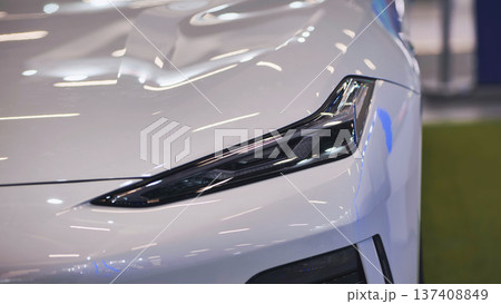 Detail of modern white car headlight reflecting showroom lights 137408849